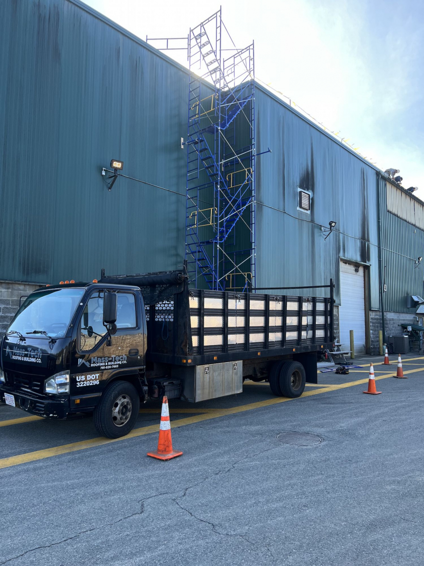 4-story green building with a MassTech truck parked in front of it with scaffolding installed